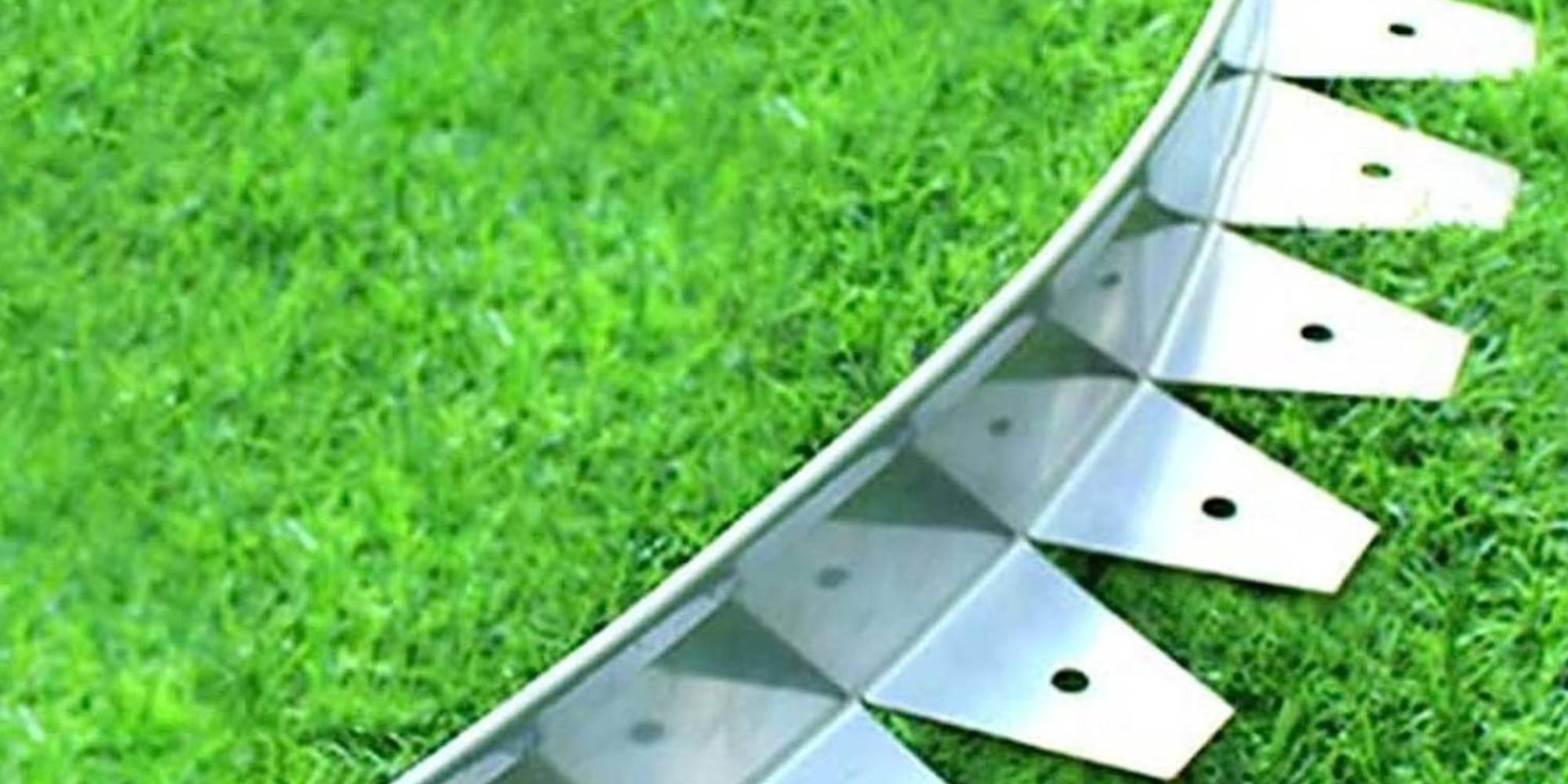 Stainless steel garden edging curving along a vibrant green lawn border, showing the clean silver finish and pre-drilled stake holes